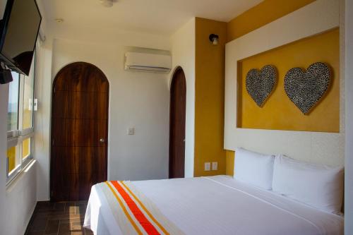 a bedroom with a bed with two hearts on the wall at Hotel Happy Beach in Zihuatanejo