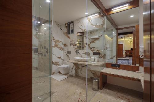 a bathroom with a glass shower and a toilet at Hotel Aditya Mansingh Inn in Somnath