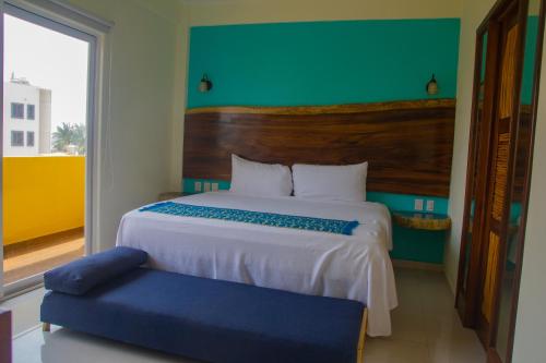a bedroom with a large bed and a blue chair at Hotel Happy Beach in Zihuatanejo