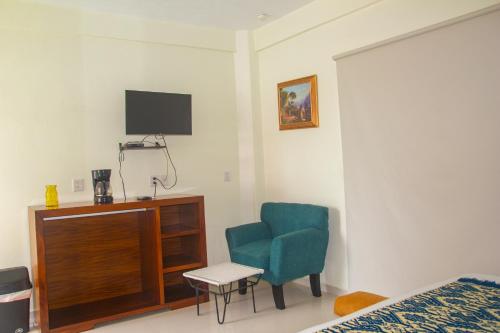 a bedroom with a blue chair and a tv at Hotel Happy Beach in Zihuatanejo