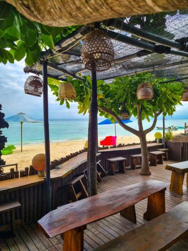 una terraza de madera con mesas y sillas en la playa en Lembongan Made Inn, en Nusa Lembongan