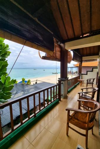 Un balcón con sillas y vista a la playa. en Lembongan Made Inn, en Nusa Lembongan