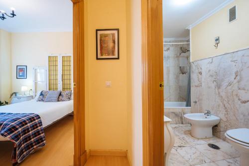 y baño con cama, aseo y lavamanos. en Precioso Apartamento San Juan de la Palma, Parking Optional, en Sevilla