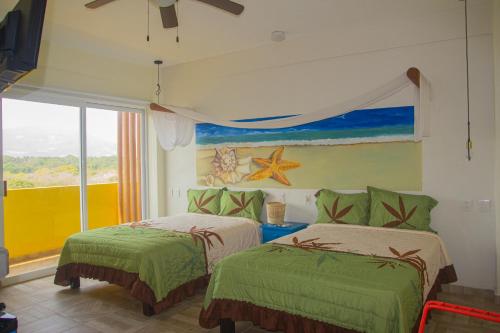 a bedroom with two beds and a painting on the wall at Hotel Happy Beach in Zihuatanejo