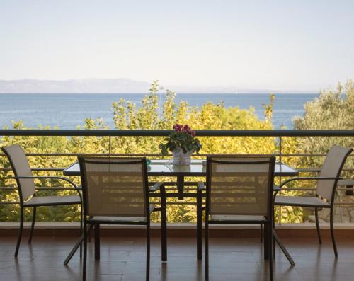 a table with chairs and a vase of flowers on a balcony at Karantou in Tiros