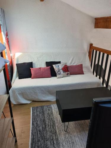 1 dormitorio con cama blanca y almohadas rojas en Maison à 200m de la plage. T3 avec terrasse., en Valras-Plage