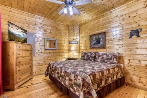 a log cabin bedroom with a bed and a ceiling fan at Papa's Bear Nest in Sevierville