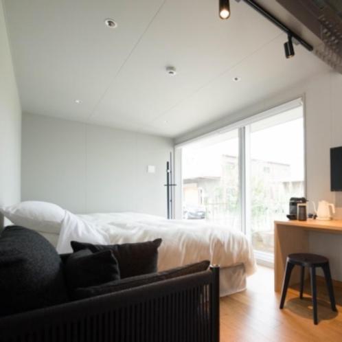 a white bedroom with a bed and a table with a chair at arita huis in Arita