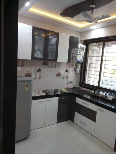 a kitchen with white cabinets and a refrigerator at Vista Manor - 3 BHK with pool-1.5 hrs from Mumbai in Pālghar