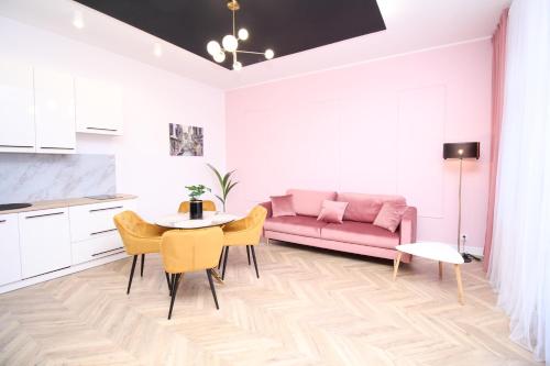 a living room with a pink couch and a table at Apartament Przytulny in Szczawno-Zdrój