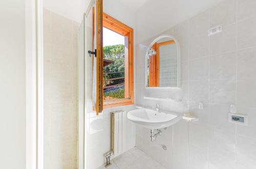 a white bathroom with a sink and a window at Villino Garden & Pool in Marina di Andora