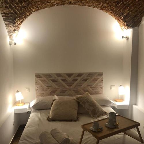 a bedroom with a bed with a table and two lamps at Apartamento Stark in Cáceres