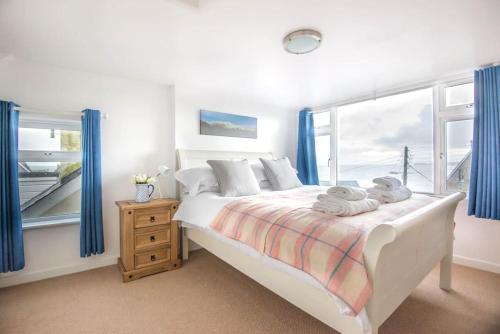 a bedroom with a bed with blue curtains and a window at Tregenna, Port Isaac Bay Holiday in Port Isaac