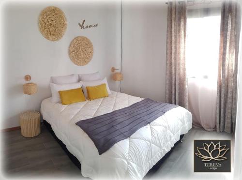 sypialnia z dużym łóżkiem z żółtymi i niebieskimi poduszkami w obiekcie Téréva Lodge - La villa de standing w mieście Cilaos