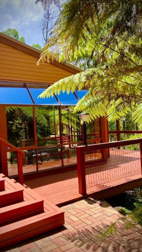 eine Holzterrasse mit einer Treppe und einem blauen Schirm in der Unterkunft Melbourne Topview Villa in Dandenong ranges near Skyhigh in Kalorama