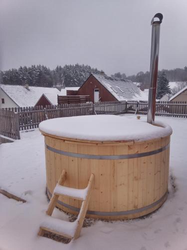 a wooden barrel in the snow with a sled at Ubytování u Kapličky in Kunějov