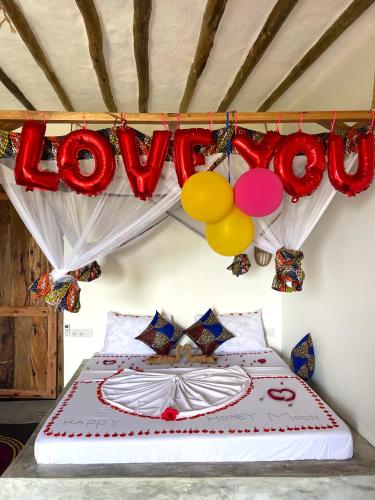 a bed with a sign that says love and balloons at Chunga Changa in Matemwe