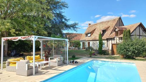 einen Pool mit Stühlen und einen Pavillon neben einem Haus in der Unterkunft En pleine campagne, proche du Mans - chambre d'hôtes in Fillé