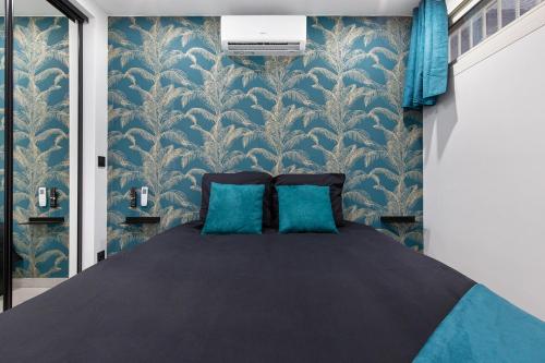 1 dormitorio con 1 cama con papel pintado azul y blanco en Double Jeu- NATURISTE VILLAGE-SPA-Clim-2 BEDROOM-Parking-90m2 en Cap d'Agde