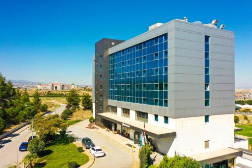 デニズリにあるPark Dedeman Denizliの駐車場付きの高いガラス張りの建物