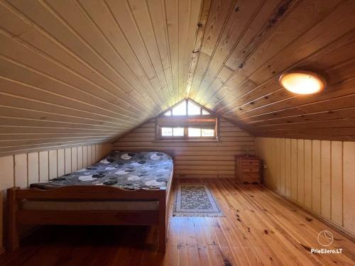 a room with a bed in a wooden room with a window at Resort by Nava Lake in Aukštadvaris