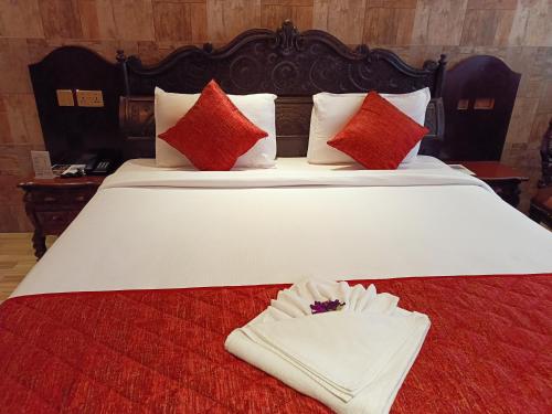 a large white bed with red pillows and a towel at HYDERS PARK- THE LUXURY HOTEL in Kodaikānāl