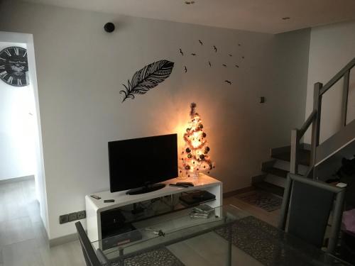 un salon avec une télévision et un arbre de Noël dans l'établissement Maisonnette cosy à Châtillon-Coligny, à Châtillon-Coligny