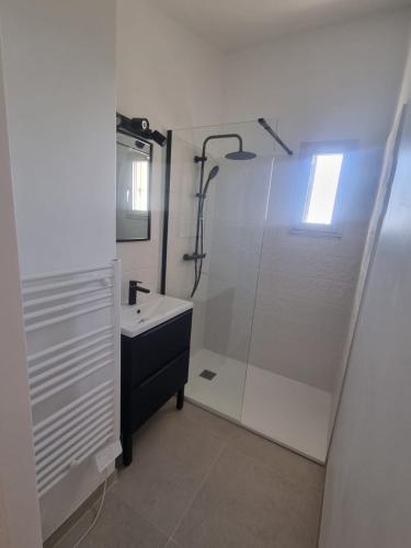 une salle de bain blanche avec une douche et un lavabo dans l'établissement Agde : Appartement 2 chambres au bord des falaises, au Cap d'Agde
