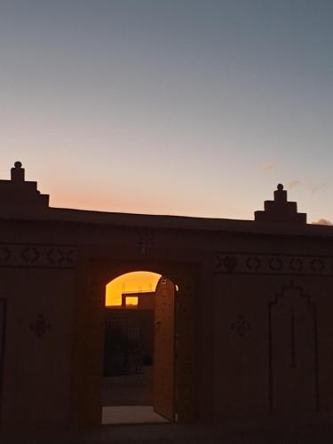 a building with an open door with the sunset in the background at Maison d'hôtes IZZA in Kalaat MGouna