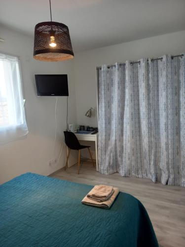 1 dormitorio con cama, escritorio y ventana en Chambre d'hôtes Entre mer forêt et marais, en Olonne-sur-Mer