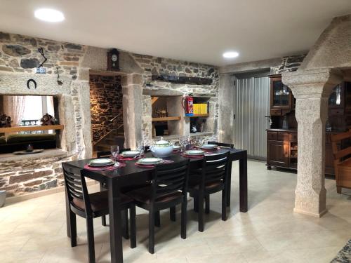 a dining room with a black table and chairs at Casa do Grallo in Corcoesto