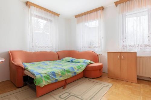 a couch with a blanket on it in a room with windows at Apartma Ana in Preserje