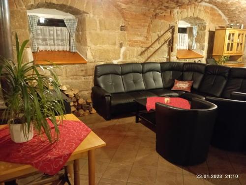 a living room with a black leather couch and tables at Chalupa-statek Arkáda in Božanov