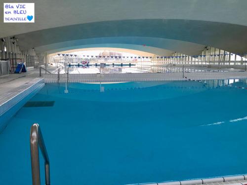 een groot zwembad met blauw water in een gebouw bij Studio Mezzanine La vie en bleu- Vue mer Deauville in Deauville