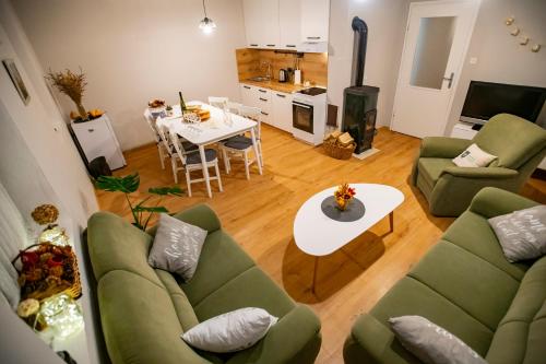 a living room with two green couches and a table at Krijesnica in Pušina