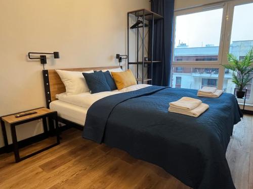 sypialnia z łóżkiem z niebieską pościelą i oknem w obiekcie PM. Apartments Krakow w Krakowie