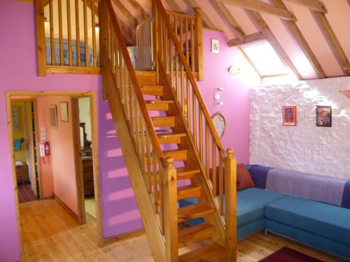 una escalera de madera en una habitación con paredes púrpuras en Long barn, en Kilgetty