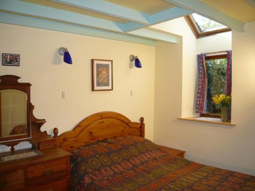 1 dormitorio con cama, espejo y ventana en Long barn, en Kilgetty