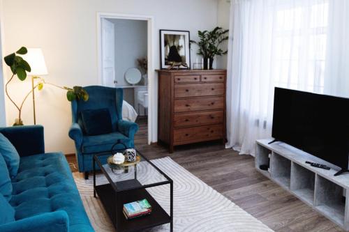 un salon avec un canapé bleu et une télévision dans l'établissement Charming apartment in Tallinn old town!, à Tallinn