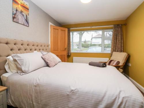 a bedroom with a large white bed and a window at The Hollies in Prestatyn
