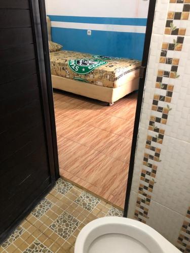 a bathroom with a toilet and a bed in a room at PENGINAPAN BANYU BIRUKu in Kota-anyar