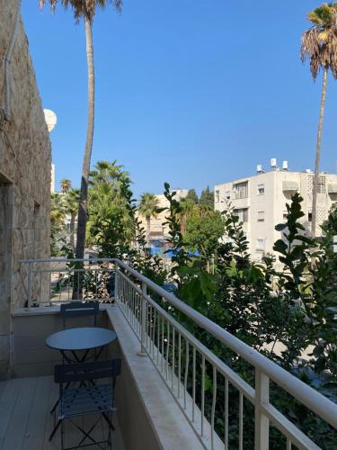 a balcony with a table and chairs and palm trees at Bat Galim - by the sea in Haifa