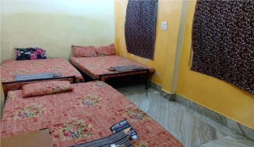Zimmer mit 3 Betten und einem Spiegel in der Unterkunft Maheshwari Bhavan By WB Inn in Sītāpur Mūāfi
