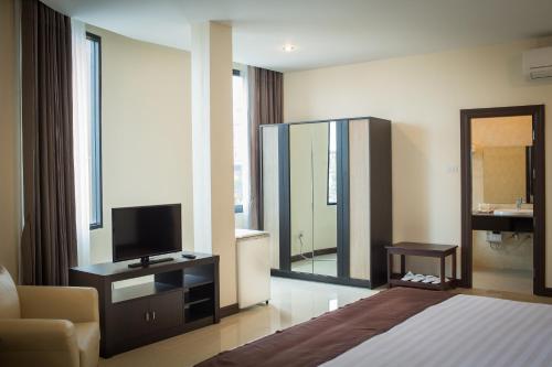 una camera con letto, TV e specchio di Centerpoint Boutique Hotel a Vientiane