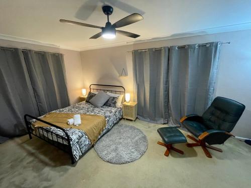Green PointSpacious 4BR getaway with panoramic water & mountain view的一间卧室配有一张床、风扇和椅子