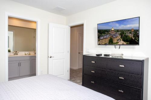 een slaapkamer met een bed en een tv aan de muur bij Stunning 8 Bd w/ Pool Close to Disney 2887 in Kissimmee