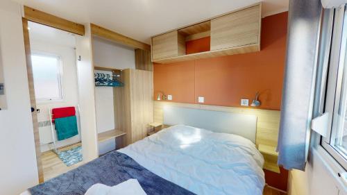 Un dormitorio pequeño con una cama y una ventana. en Mobil home domaine avec piscine proche mer, en La Parée Preneau