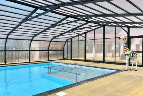 - une grande piscine avec une girafe joueuse dans un bâtiment dans l'établissement Mobil home domaine avec piscine proche mer, à La Parée Preneau