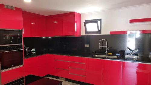 una cocina roja con armarios rojos y fregadero en Lombada House en Ponta Delgada