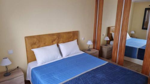 1 dormitorio con cama azul y espejo en Lombada House en Ponta Delgada